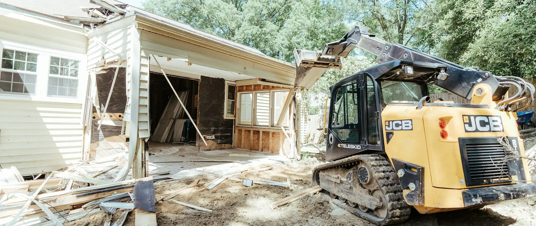 Compact loader parked beside a house during foundation drainage work