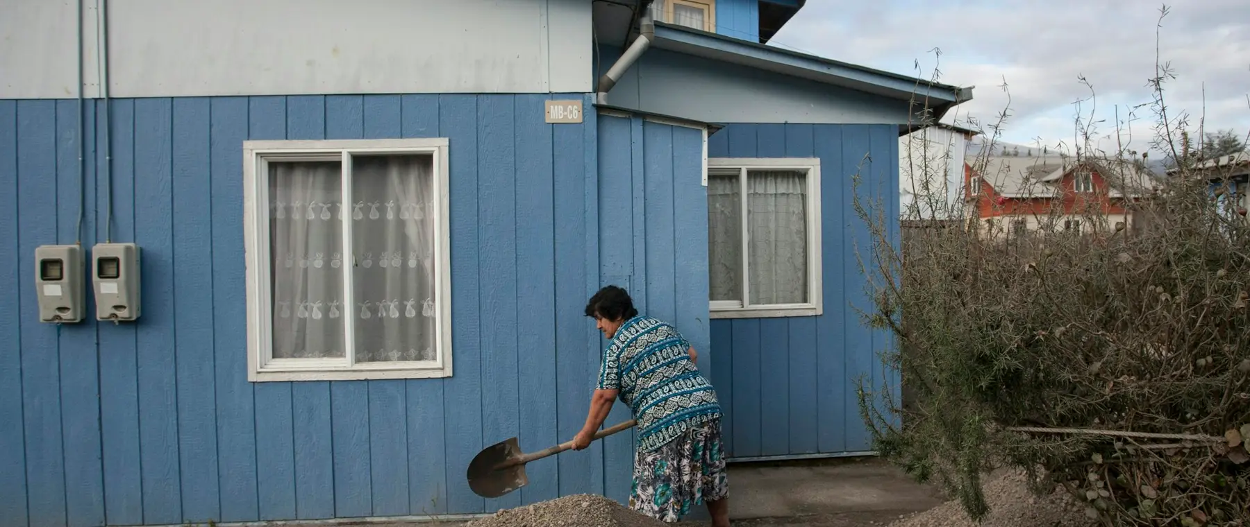Gravel being shovelled into place beside a blue-sided house