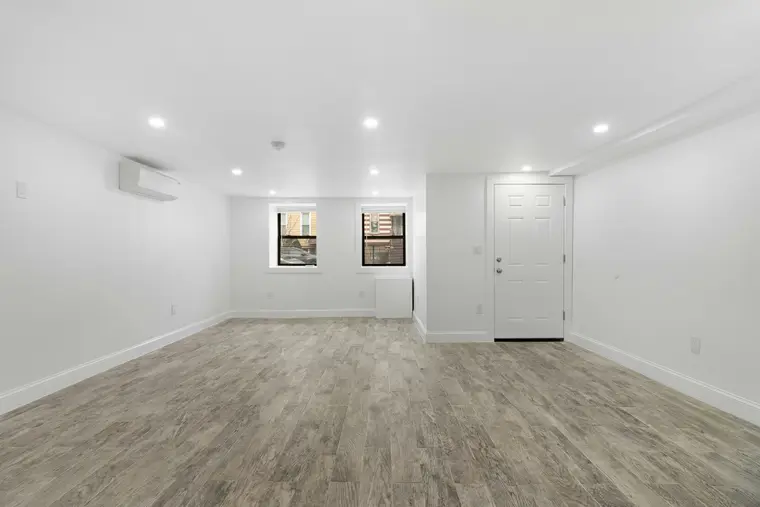 Empty finished basement room with new flooring and painted walls