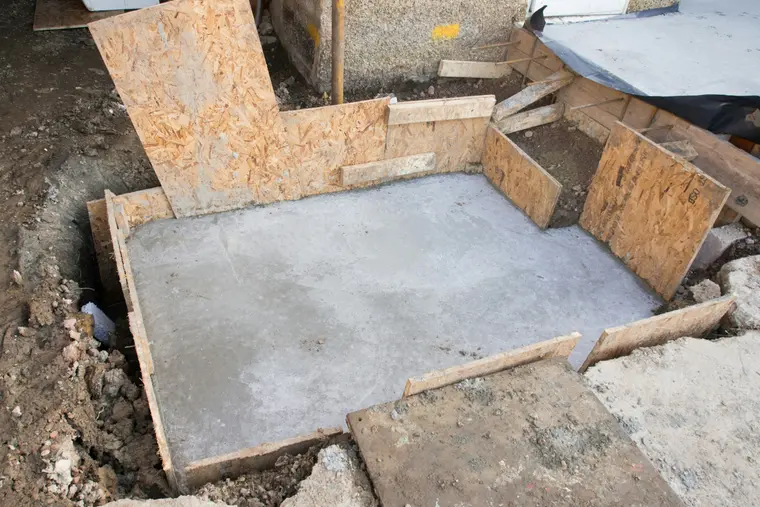 Freshly poured concrete footing in a small residential excavation