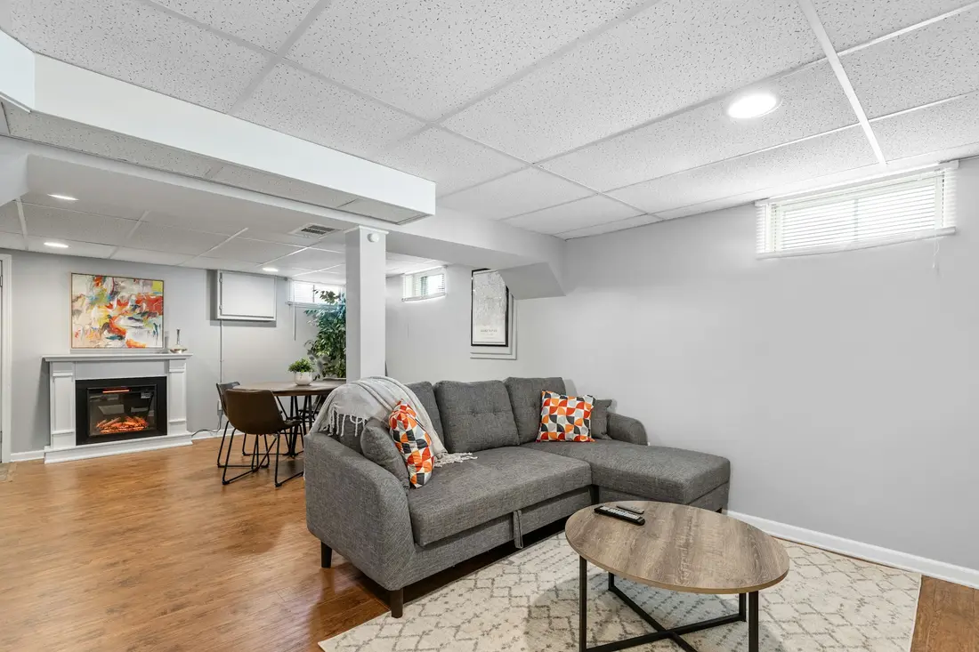 Furnished basement living area with a sofa, fireplace and finished flooring