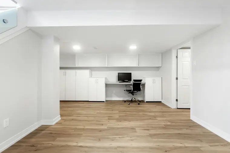 Basement home office with built-in cabinets and a desk