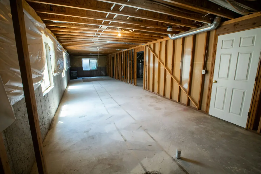 Unfinished basement with framing, bare concrete floor and exposed services