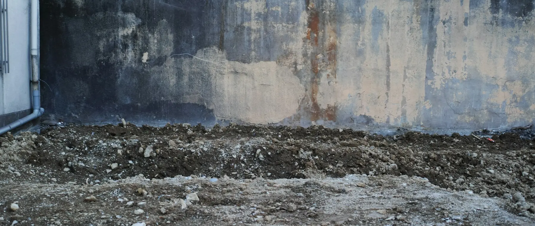 Concrete foundation wall with damp staining along its base