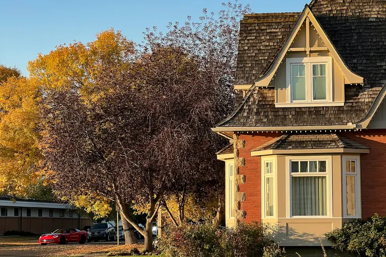 Two-storey brick house with a bay window under autumn trees