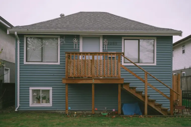 Blue-sided bungalow with a raised wooden deck and stairs