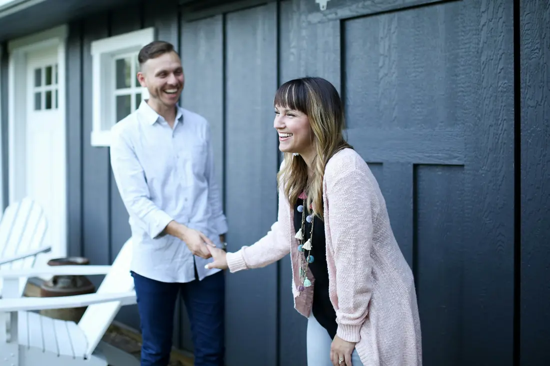 Two people greeting each other at the front door of a house