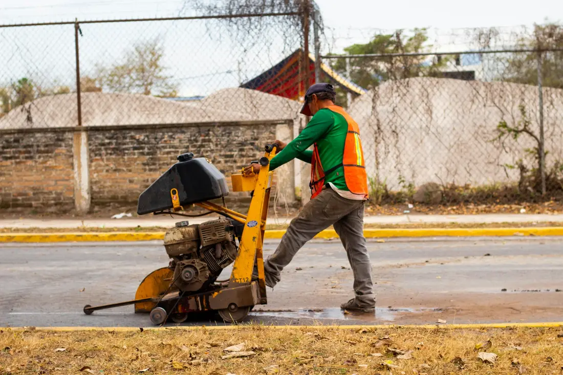 Walk-behind concrete saw cutting a straight line through a slab