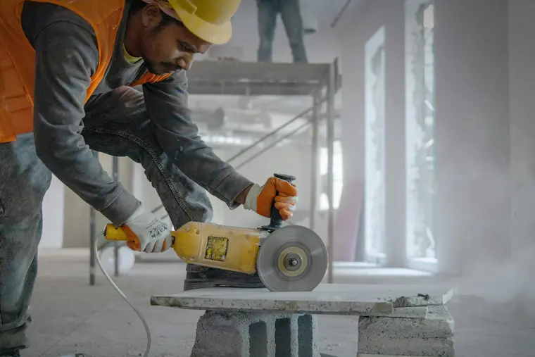 Hand-held cut-off saw slicing concrete with dust in the air