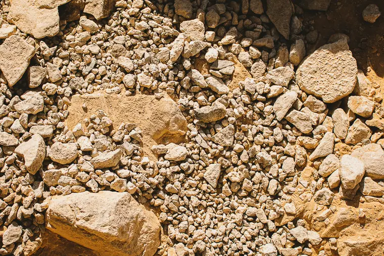 Excavated fill and broken limestone rubble beside a foundation