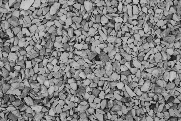 Grey angular crushed stone of the size used around a perforated drain