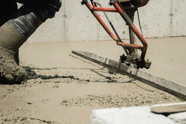 Hands working fresh concrete smooth with a float