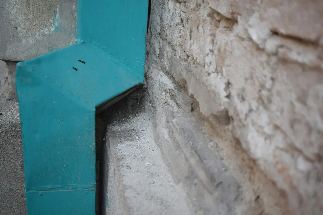 Waterproofing membrane and flashing sealed at the base of a foundation wall